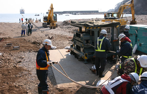 2014年4月20日7時30分　これが陸側です。海底ケーブル先端に取り付けたロープを重機が巻き取りながら、ケーブルを引き揚げます。